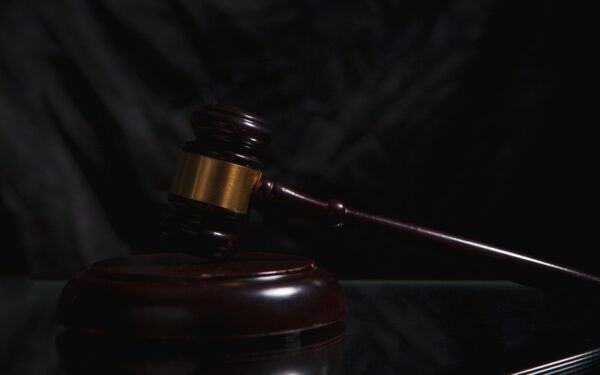 A wooden gavel rests on a dark surface.